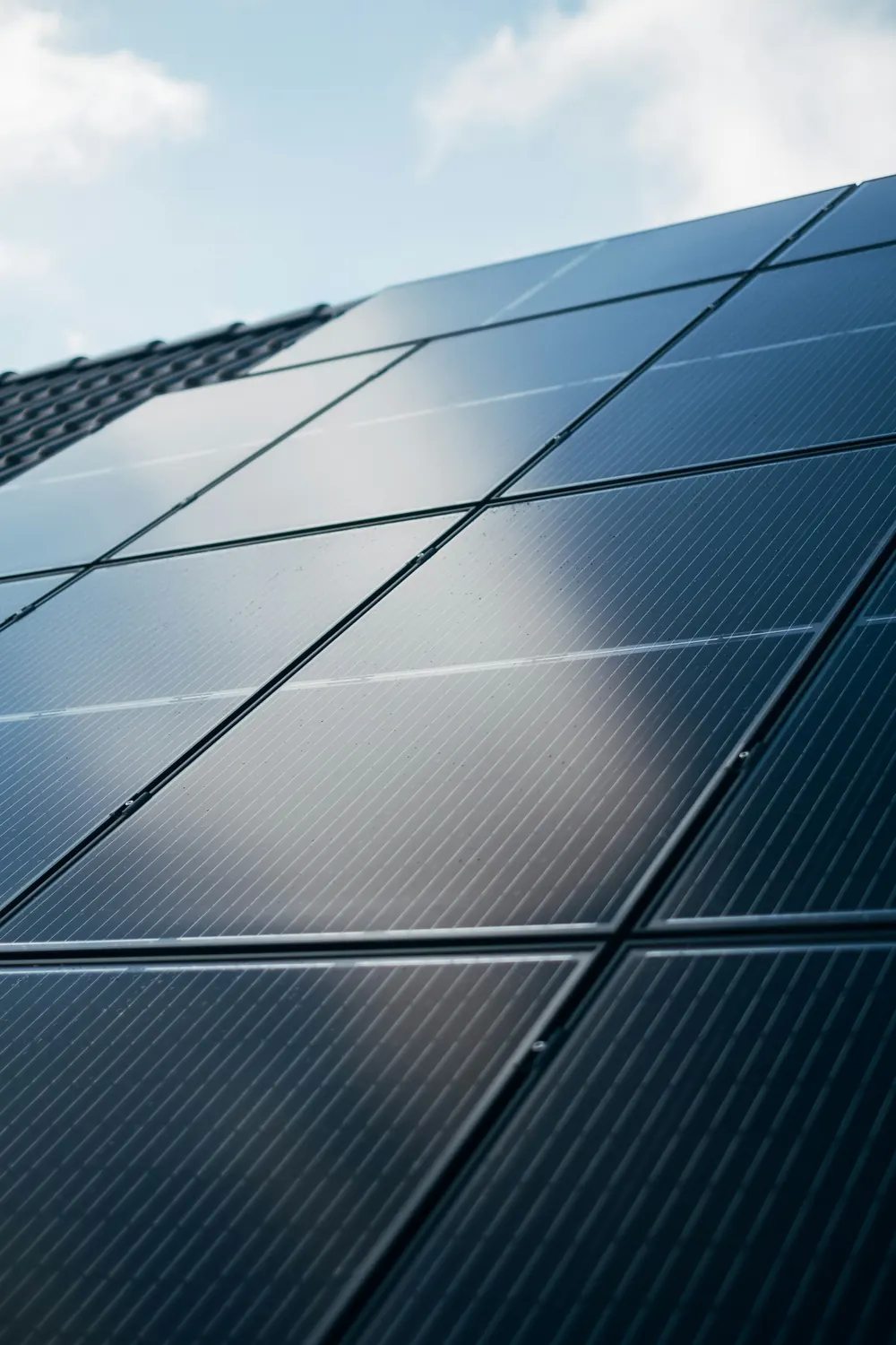 Dunkles Solarmodul auf einem Dach vor blauem Himmel